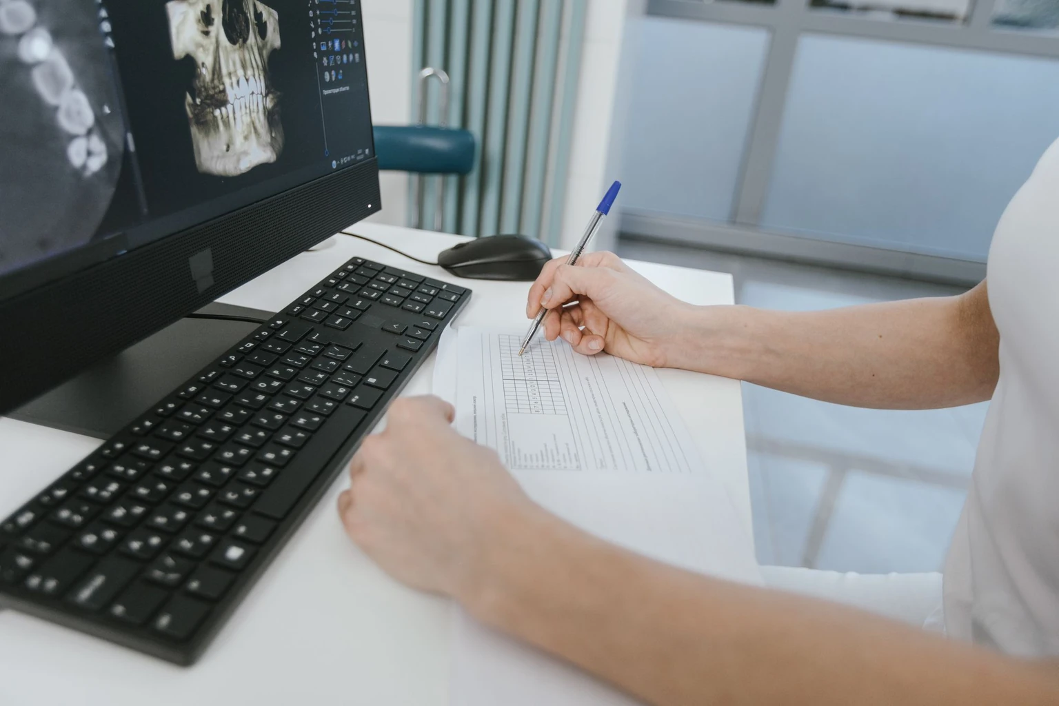 A dental expert reviewing imaging and preparing a written report at a workstation